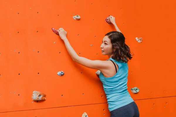 Menina escalando em um treinamento de parede de escalada em bouldering ginásio — Fotografia de Stock