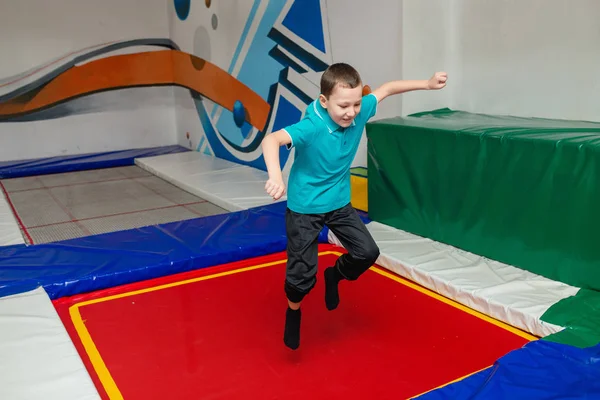 Pojken hoppar högt i randiga tights på stora studsmattan i k — Stockfoto
