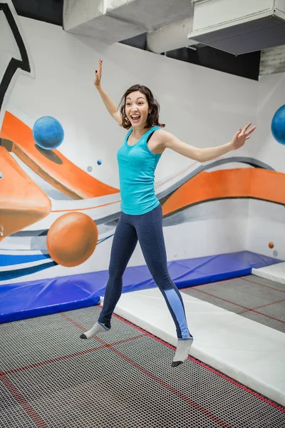 Молодая спортсменка прыгает на батуте в фитнес-парке и делает упражнения в помещении — стоковое фото