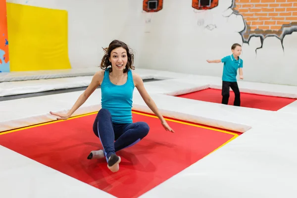 Matka a její syn skákání na trampolíně společně uvnitř v posilovna. — Stock fotografie