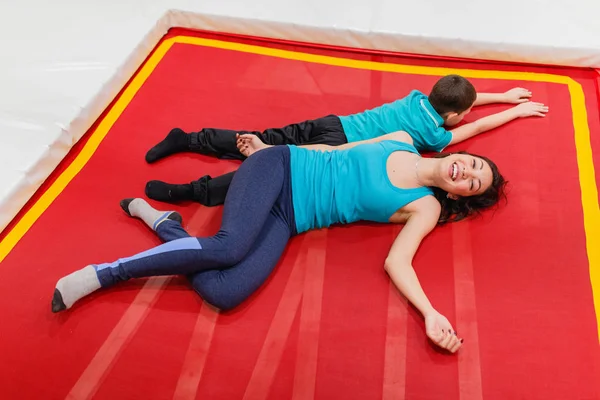 Anne ve oğlu yalan ve üzerinde trambolin birlikte kapalı dinlenme fitness salonunda.