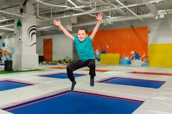 Joven niño de 6 años saltando en una cama elástica en el gimnasio de fitness para niños — Foto de Stock