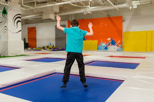 Joven niño de 6 años saltando en una cama elástica en el gimnasio de fitness para niños —  Fotos de Stock