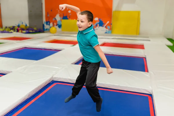 Joven niño de 6 años saltando en una cama elástica en el gimnasio de fitness para niños — Foto de Stock