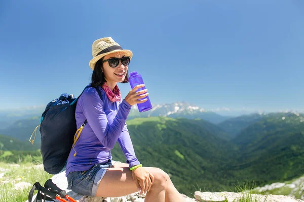 여성 여행자는 산에 산 및 병에서 식용 수 위에 앉아 — 스톡 사진