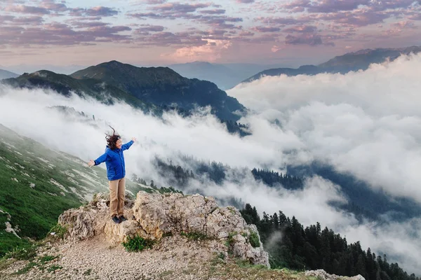 Молода щаслива жінка насолоджується видом на великий туманний пейзаж на вершині гори — стокове фото
