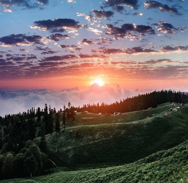 Hermoso atardecer en las montañas con niebla y nubes y pequeñas casas pastores —  Fotos de Stock