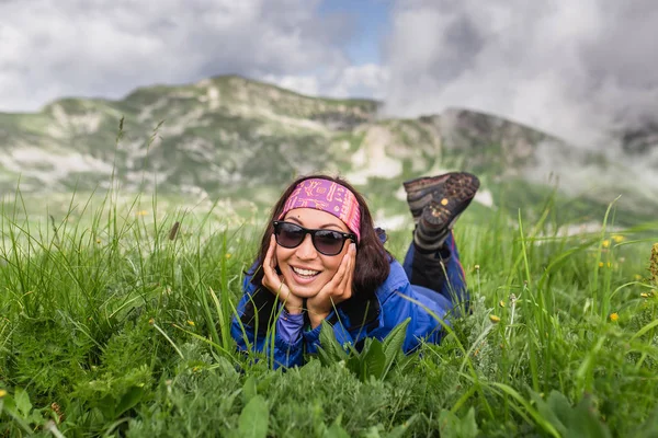 Mujer joven relajándose en la hierba en los prados alpinos altos en el día de senderismo — Foto de Stock