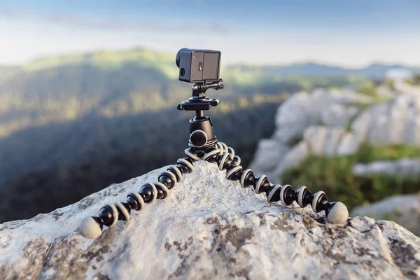 Action camera mounted on a tripod gorilla with summer mountains in the background