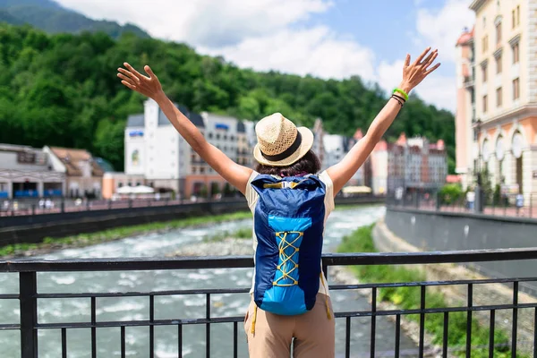 Vista da parte de trás de uma mulher com mochila desfrutando de vista para a cidade a partir da ponte sobre o rio — Fotografia de Stock