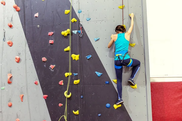 Bela jovem mulher começa a escalar grande parede artificial — Fotografia de Stock