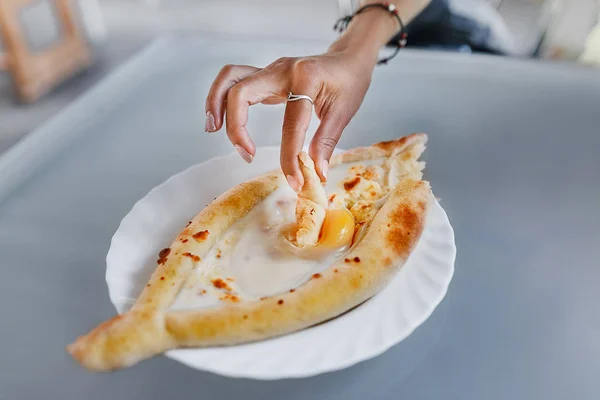 Nainen käsi yrittää maistaa khachapuri ravintolassa — kuvapankkivalokuva