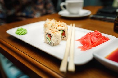Rulo suşi yemek çubukları ve soya sause ile restoran siyah ahşap tablo