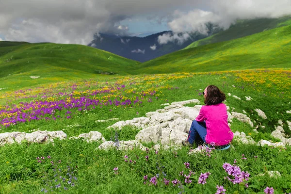 Mulher bonita sentada no topo da montanha e olhando para a paisagem — Fotografia de Stock