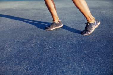 Kadın atlet bacaklar ve ayakkabı kapak yolda eylem açık havada gün batımında.