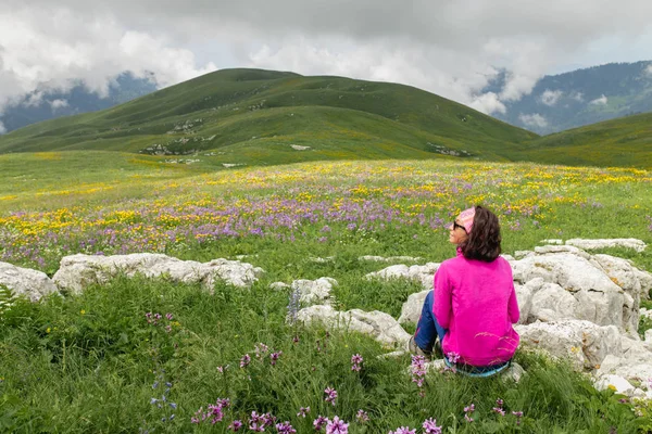 Beautiful woman sitting on mountain top and looking at the landscape