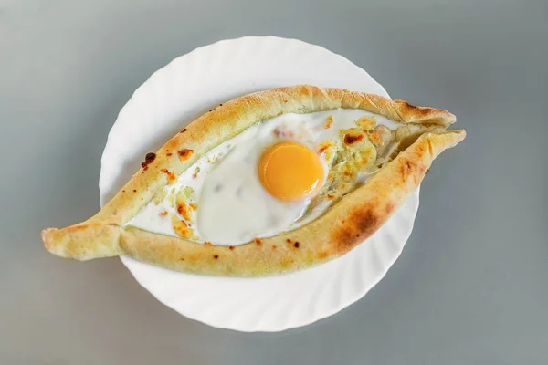 Abjasia o georgiano plato nacional pan Khachapuri con queso y huevo en un plato en una cafetería — Foto de Stock