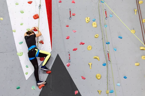 Belle jeune femme commence à escalader grand mur artificiel — Photo