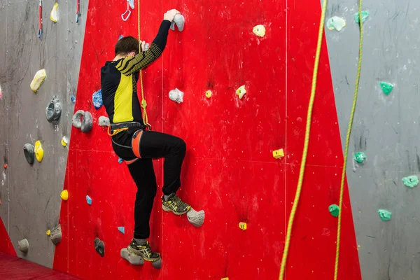 Kaukasische jongeman opleiding op kunstmatige klimmen binnenshuis — Stockfoto