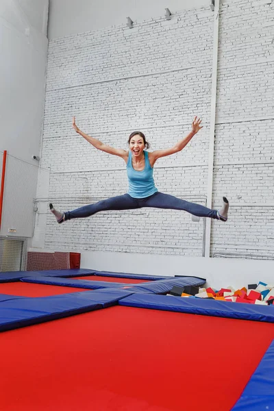 Mladá žena v trampolína sport centru uvnitř na lyžích — Stock fotografie