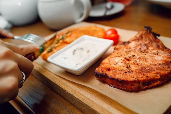 Pork steak with hashbrowns on a wooden plate in restaurant — Stock Photo, Image