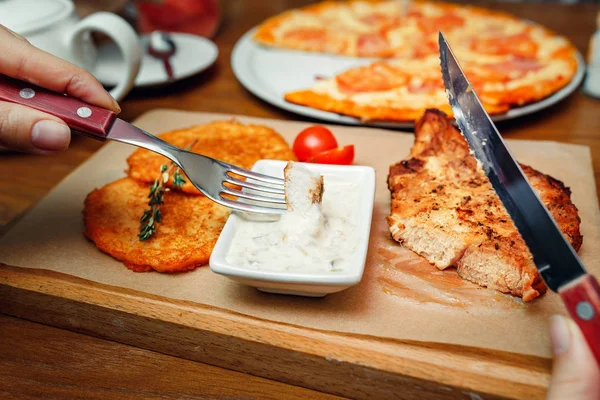 Woman eating with a fork and a knife pork steak in a restaurant — Stock Photo, Image