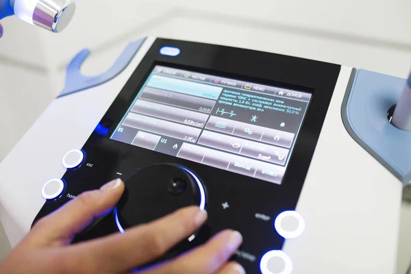 The doctor at the clinic sets up the device for ultrasound therapy, close-up on hands — Stock Photo, Image