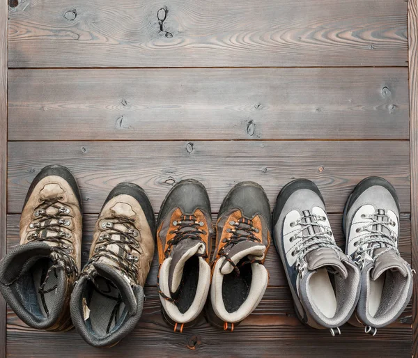 Много пеших и треккинговых ботинок для путешествий на деревянном фоне — стоковое фото