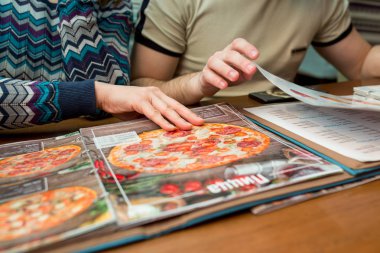 FEBRUARY 23, 2017, UFA, RUSSIA: Two people choose a pizza from the menu in the restaurant 