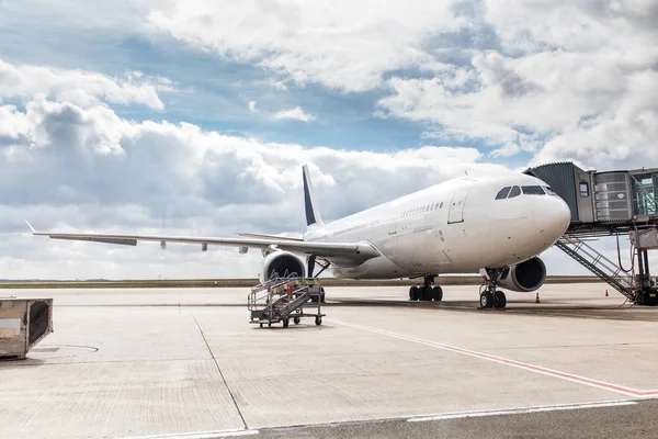 El avión blanco irreconocible en el aeropuerto lleva a los pasajeros a través de una escalera telescópica — Foto de Stock