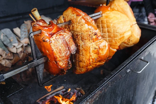 Un grand morceau de jambon de porc est cuit sur un feu ouvert dans le gril. Rue nourriture tchèque — Photo