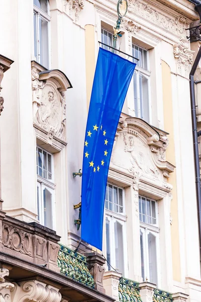 De tolv gula stjärnor flagg Europeiska unionen vinka från fasaden av en gammal byggnad. — Stockfoto