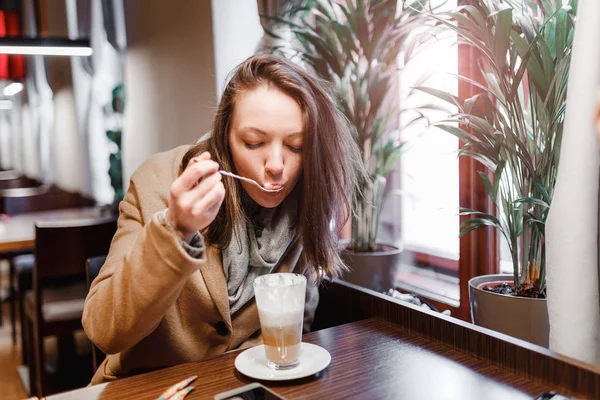 Молодая женщина пьет кофе в помещении городского кафе — стоковое фото