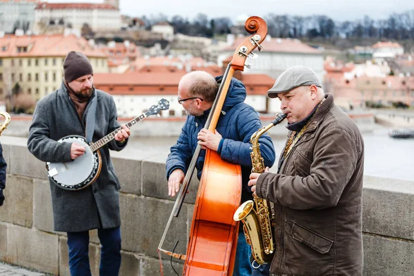 Prague, Çek Cumhuriyeti - 18 Mart, 2017: Street band müzisyen Charles Köprüsü'nde Prag'ın merkezi çello, saksafon ve banjo oynamak — Stok fotoğraf