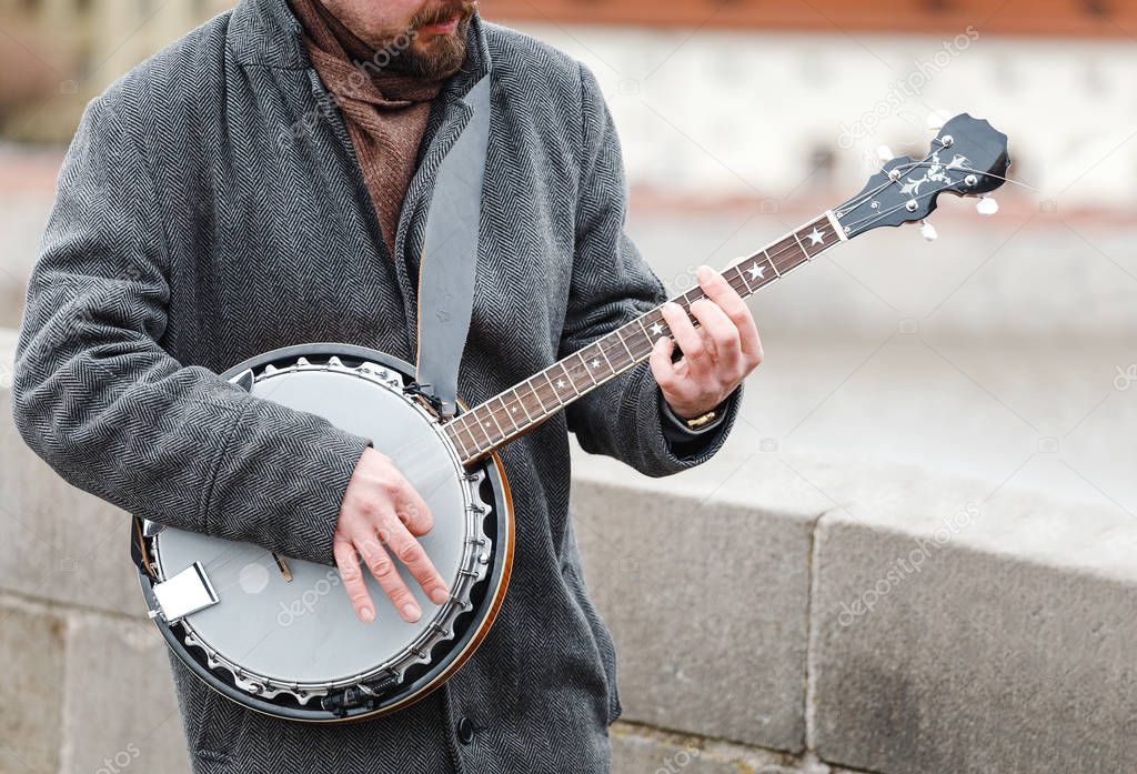 A street musician playing a banjo in the open air
