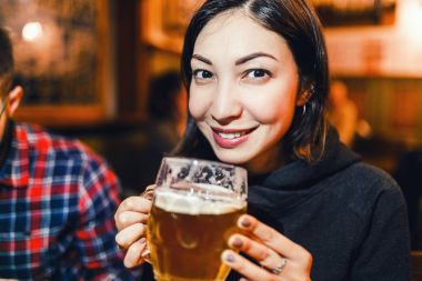 Asian woman drinking beer in a traditional Czech beer house in Prague clipart