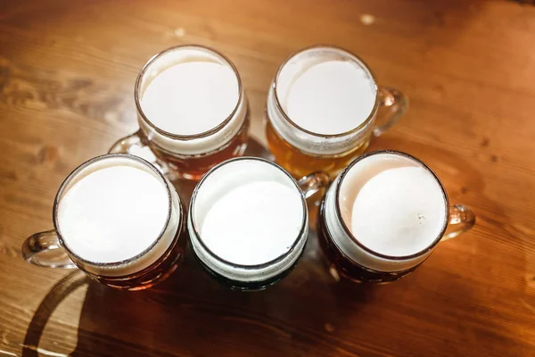 Cinco auténticas tazas de cerveza checa en el pub de Praga sobre la mesa. Los tipos diferentes de la cerveza - claro, oscuro y herbario — Foto de Stock