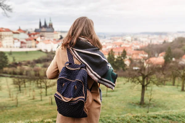 Mujer turista en un abrigo con una mochila viaja en el parque de la ciudad de Praga, vista trasera — Foto de Stock