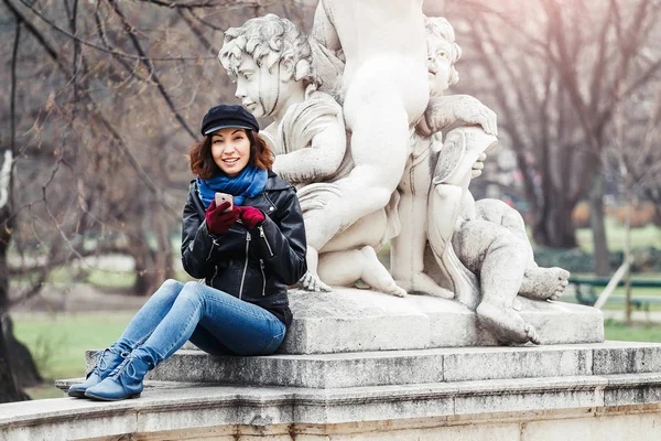 Junge brünette Reisende Frau spricht und nutzt Handy im Garten, Roaming und Telefonverbindung im Ausland Konzept — Stockfoto