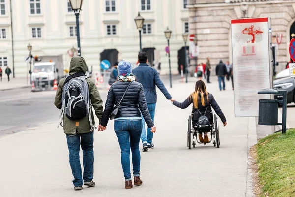 Egy férfi, egy nő megy a kezét Bécs utcáin, a háttérben a másik pár a szerelem a kerekesszékben, fogyatékkal élő szeretet fogalma — Stock Fotó