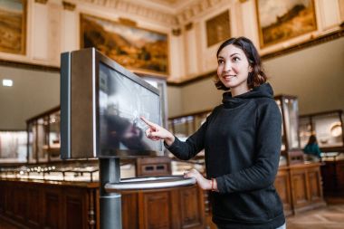 Müzenin bir kadında dokunmatik monitör elektronik kılavuz, modern eğitim kavramı kullanır