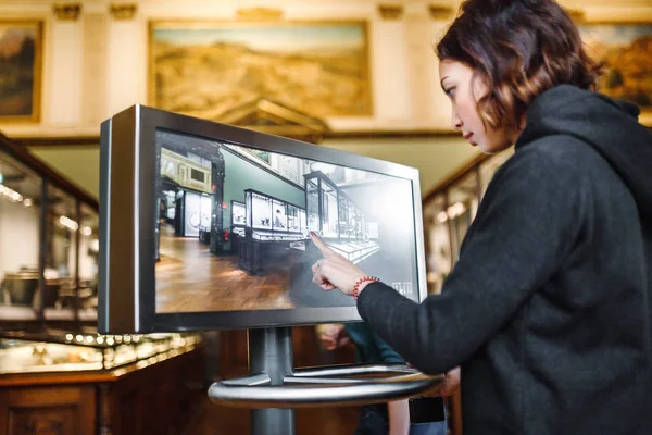 Женщина в музее использует сенсорный монитор электронного гида, концепцию современного образования — стоковое фото