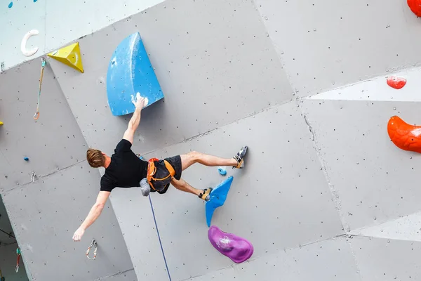Спортсмен-альпинист висит на искусственной скалолазающей стене, соревнование по сложности — стоковое фото