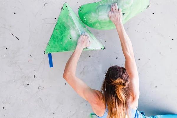 Idrottsman kvinna tränar på en sport klättervägg i bouldering gym, bakifrån — Stockfoto