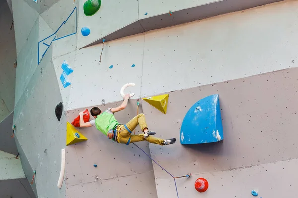 Спортсмен-альпинист висит на искусственной скалолазающей стене, соревнование по сложности — стоковое фото