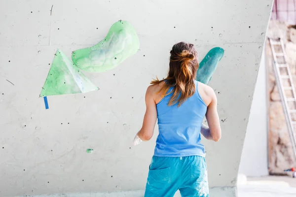 Een sport vrouw klimmer op een klimwand is het verkennen van de route in een uitstekende atletische vorm met de opluchting spieren van de armen en schouders — Stockfoto