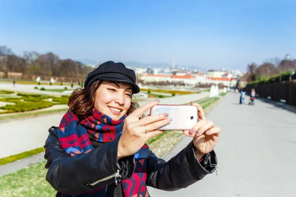 Nuori aasialainen nainen nahkatakissa tekemässä selfietä älypuhelimella Wienissä, Euroopassa — kuvapankkivalokuva