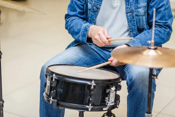 Närbild av en trummis i jeans spelar på ett musikinstrument — Stockfoto