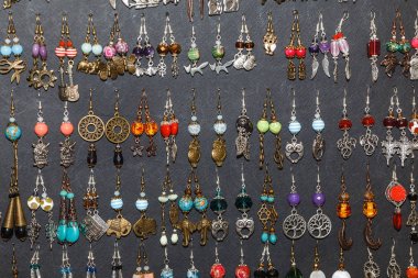 Vitrin adil pazarında satışa birçok renkli el yapımı küpe