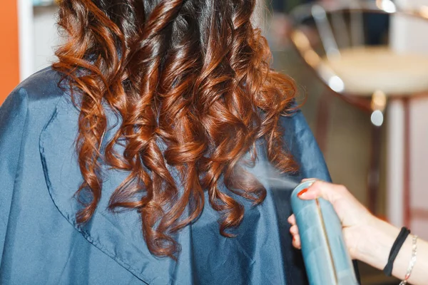 Gros plan de la tête de la femme et les mains de styliste avec de la laque à cheveux faisant coiffure bouclée au salon de beauté — Photo